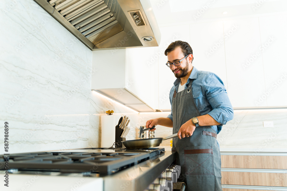 Smiling caucasian man cooking on the stainless steel stove Smiling caucasian man cooking on the stainless steel stove