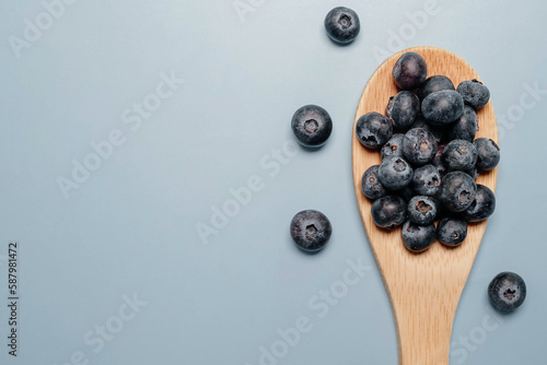 blueberries in a wooden spoon on a blue background. view from above. blueberry flat