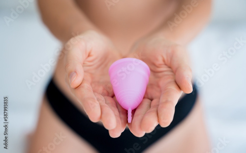 Young beautiful woman at home holding a menstrual cup in her hands