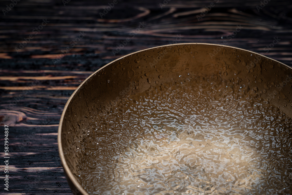 Drops of water fly into the air from hitting a Tibetan (singing) bowl ...