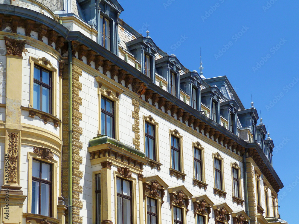 painted brown wood windows. yellow stucco elevation. old classic architecture. decorative elements. building, architecture concept. mansard roof with dormers. travel and tourism. urban scene in Europe