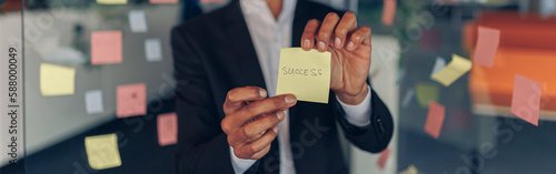 African Businessman showing sticky notes with motivational phrases while standing in office