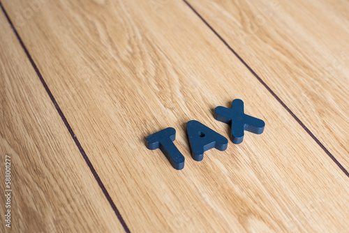 Closeup shot of wooden letter block of "TAX" on brown wooden background. 