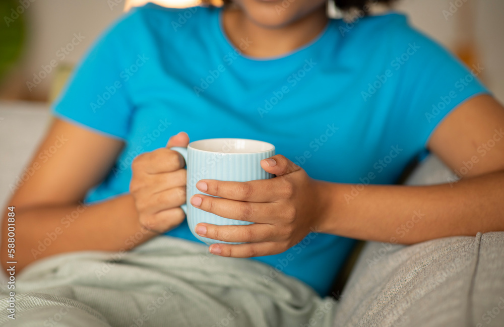 Millennial african american female enjoy relax and cup of tea on sofa in living room interior, cropped Millennial african american female enjoy relax and cup of tea on sofa in living room interior, cropped