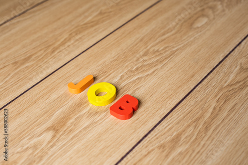 Closeup shot of colorful letter block "JOB" on wooden background. 