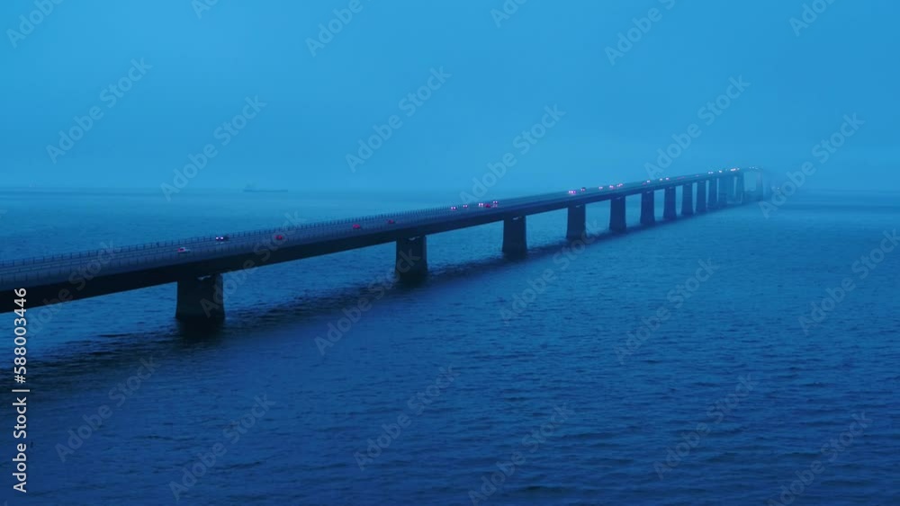 Aerial of traffic over the bridge Storebæltsbroen in Denmark. There is a heavy fog, and it is during the blue hour. 4K Aerial of traffic over the bridge Storebæltsbroen in Denmark. There is a heavy fog, and it is during the blue hour. 4K