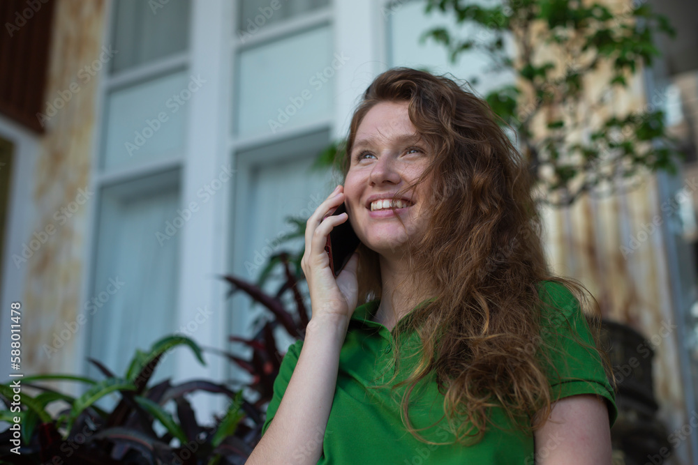 girl uses the phone on the street to call, write a message, the concept of communication, technology at summer girl uses the phone on the street to call, write a message, the concept of communication, technology at summer