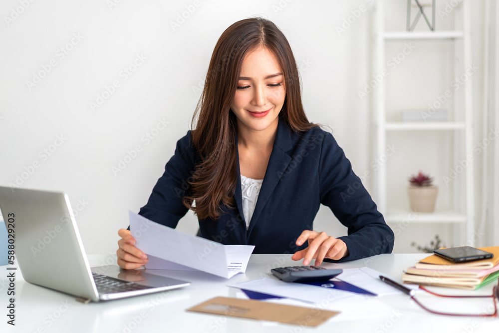 Smiling asian woman using calculator and calculate bills on laptop, paying bill, credit card, finance, tax, vat, credit card, payment, tax refund, budget, money.financial and accounting concept Smiling asian woman using calculator and calculate bills on laptop, paying bill, credit card, finance, tax, vat, credit card, payment, tax refund, budget, money.financial and accounting concept