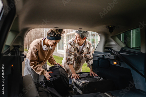 two women mother and daughter pack luggage baggage in trunk of the car