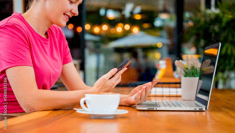 Woman using contactless payment by mobile phone with QR code at cafe