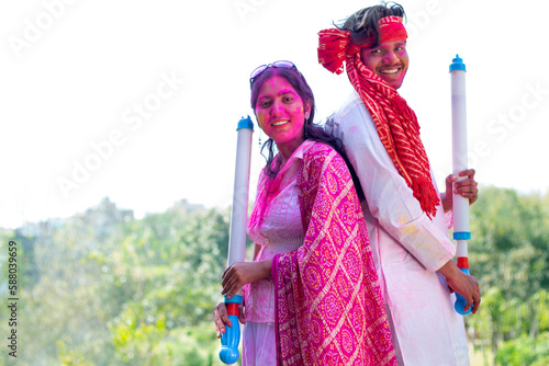 Indian young couple celebrating Holi with pichkari photo