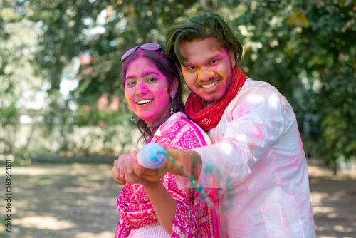 Indian young couple celebrating Holi with pichkari