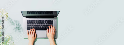 Romantic technology banner with womans hands working on laptop on blue background with flowers. Office desktop. Concept of working, communication, dating and online order on laptop. Copy space