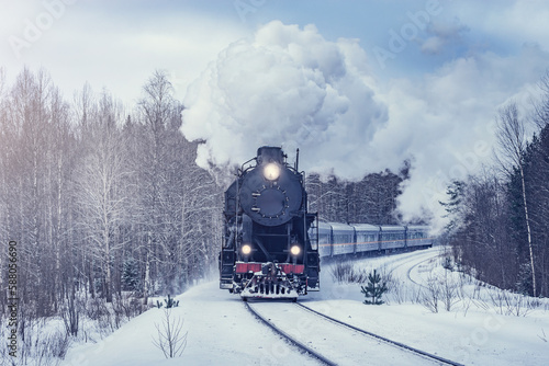 Retro steam train moves at winter morning.
