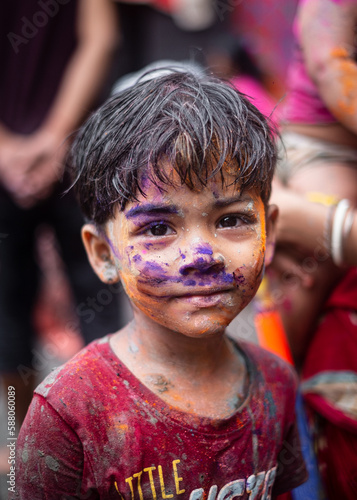 Little south asian boy smiling with colourful face in holi festival 