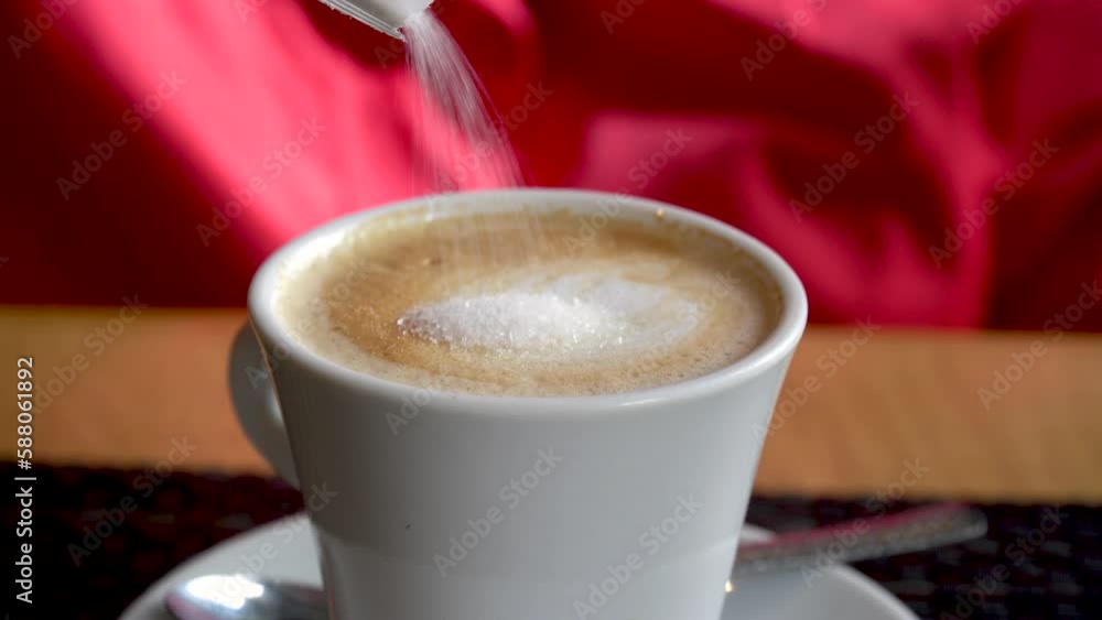 A person adds sugar to the coffee A person adds sugar to the coffee