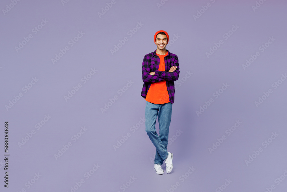 Full body smiling fun young man of African American ethnicity wear casual shirt orange hat hold hands crossed folded look camera isolated on plain pastel light purple color background studio portrait. Full body smiling fun young man of African American ethnicity wear casual shirt orange hat hold hands crossed folded look camera isolated on plain pastel light purple color background studio portrait.
