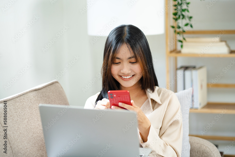 Asian Woman using cell phone sitting on couch. Asian Woman using cell phone sitting on couch.