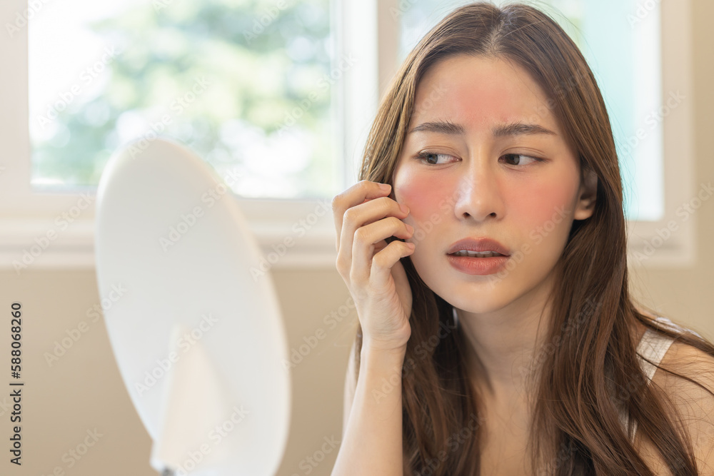 Dermatology, puberty asian young woman, girl looking into mirror, allergy presenting an allergic reaction from cosmetic, red spot or rash on face. Beauty care from skin problem by medical treatment. Dermatology, puberty asian young woman, girl looking into mirror, allergy presenting an allergic reaction from cosmetic, red spot or rash on face. Beauty care from skin problem by medical treatment.