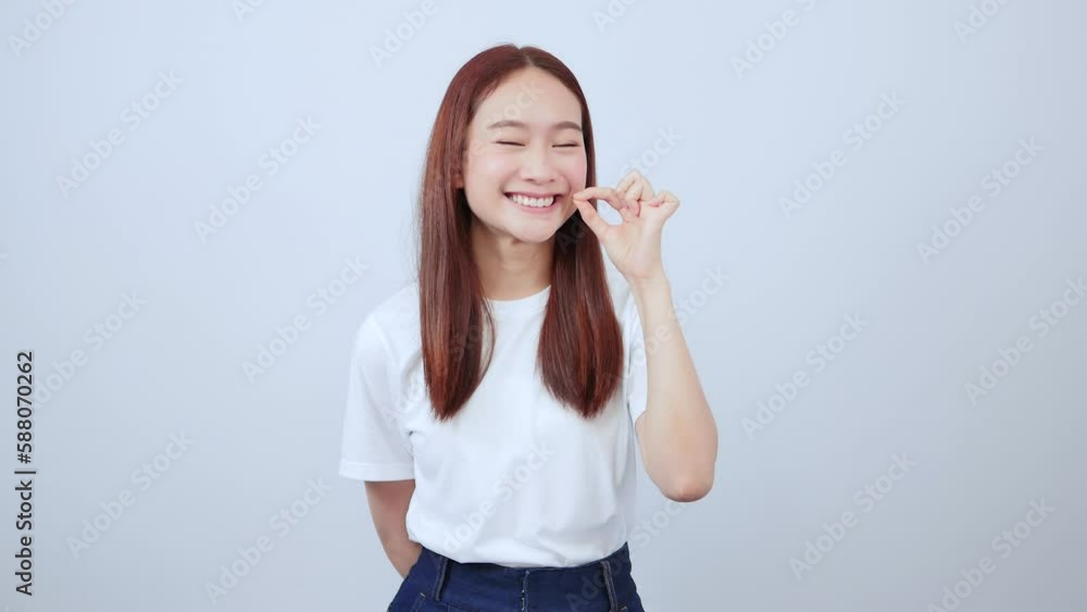 Close up young Asian woman presses her lips showing prohibition, do not speak, keep quiet, hide secrets, standing over white background. Close up young Asian woman presses her lips showing prohibition, do not speak, keep quiet, hide secrets, standing over white background.