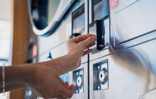 Slika na platnu Young woman putting coin in washing machine at laundry