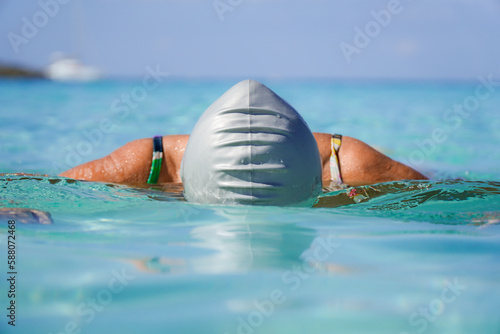 Sticker woman swimmer with a swimming cap swimming in the island turquoise sea water