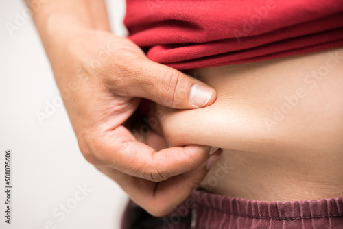 Wallpaper Mural Red shirt man using his hand to squeeze out excess fat isolated on a white background.Lose weight concept of abdominal fat surgery. Torontodigital.ca