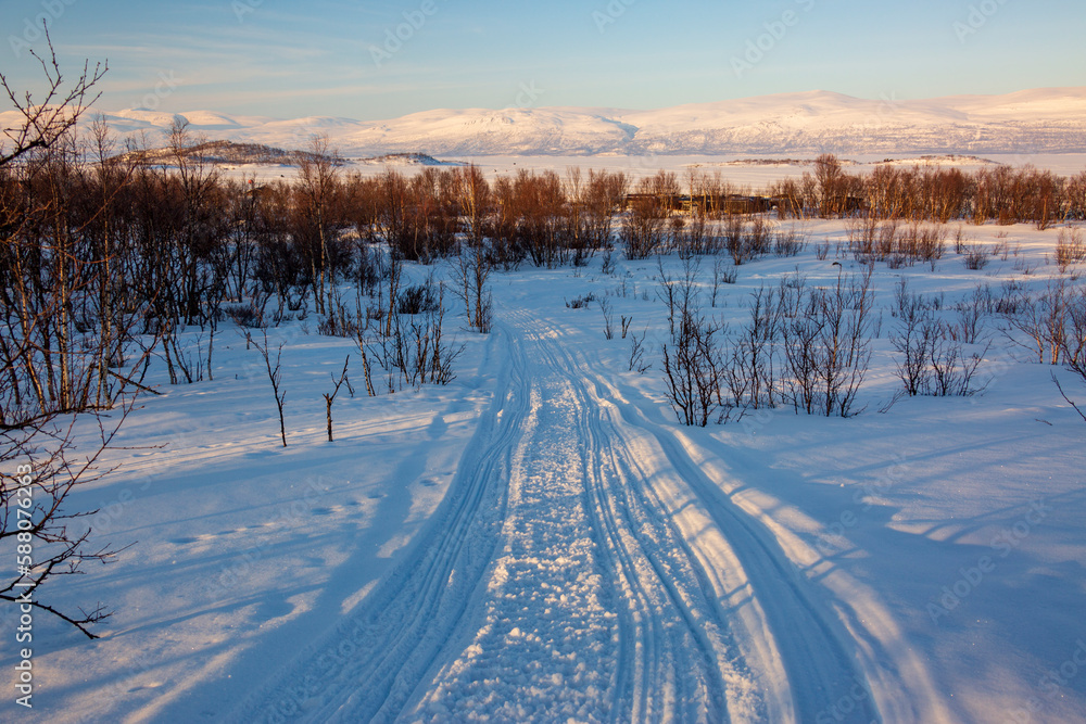 Abisko in Lapland in Sweden. Sunset at frozen Tornetrask Lake. Sun, snow, ice, the Arctic Circle, a landscape of northern Europe Abisko in Lapland in Sweden. Sunset at frozen Tornetrask Lake. Sun, snow, ice, the Arctic Circle, a landscape of northern Europe
