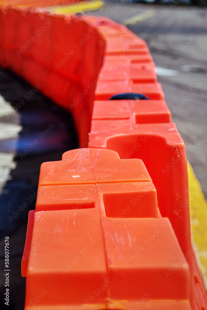 Orange heavyduty plastic barriers are set up on the sidewalk while