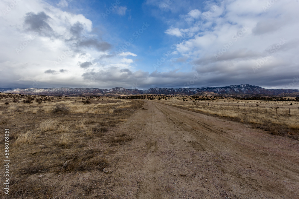 Dirt road in foreground leading to gorgeous mountain range in high desert