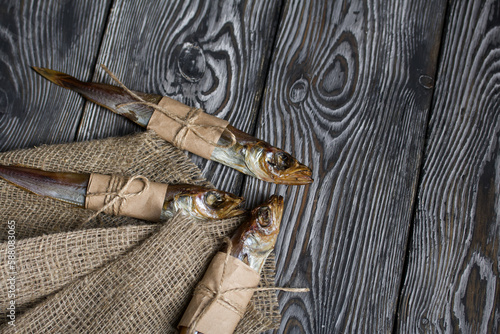 Putassu Cold smoked. The fish is wrapped with a strip of paper. Tied with linen twine. Lies on pine boards. Linen fabric. Close-up. photo