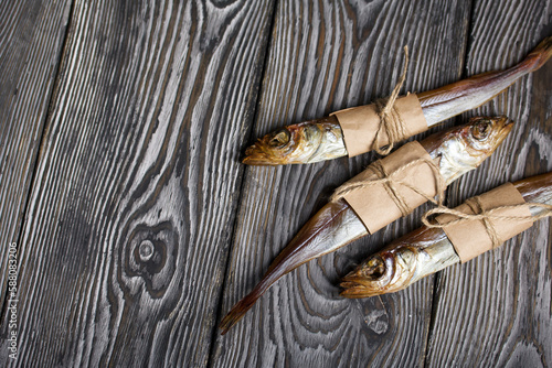 Putassu Cold smoked. The fish is wrapped with a strip of paper. Tied with linen twine. Lies on pine boards. Close-up. photo