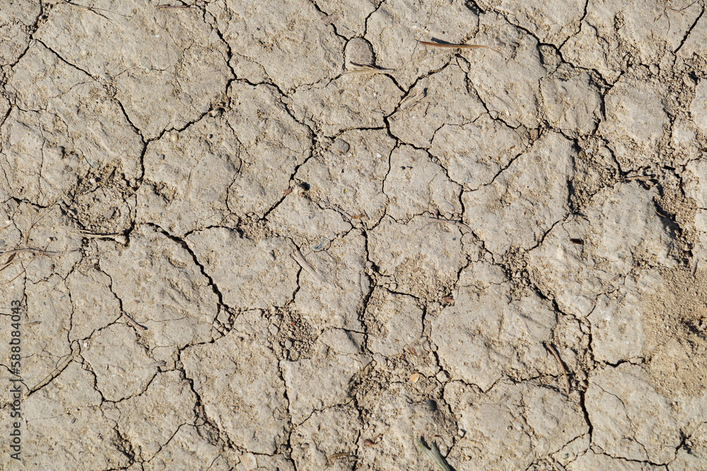 The earth is cracked from drought. Concept of drought period, parched soil, dry and barren land, lack of rainwater. Background of dry ground with cracked texture
