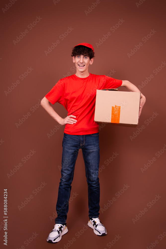 A young attractive student delivers a package. Brown background. A young attractive student delivers a package. Brown background.