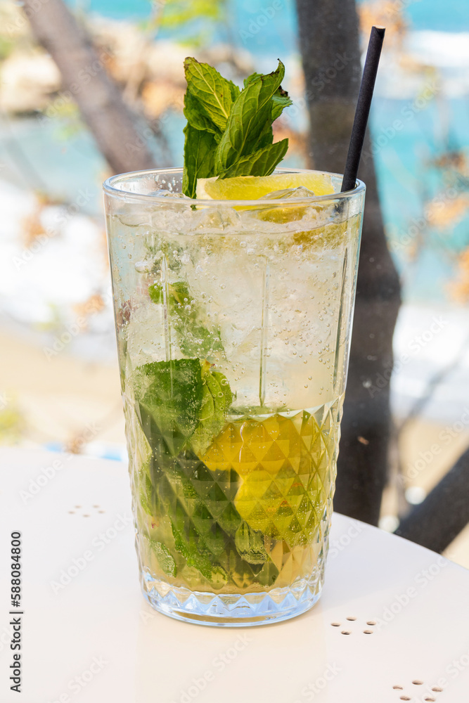 Classic Mojito cocktail with lemon and green mint leaves close-up with blurred background Classic Mojito cocktail with lemon and green mint leaves close-up with blurred background