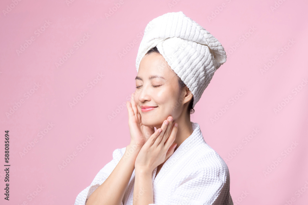 Beautiful young asian woman happy with clean face skin in towel and bathrobe, spa suit on pink background. Skincare, treatment, wellness therapy, facial care, beauty female health, cosmetology concept Beautiful young asian woman happy with clean face skin in towel and bathrobe, spa suit on pink background. Skincare, treatment, wellness therapy, facial care, beauty female health, cosmetology concept
