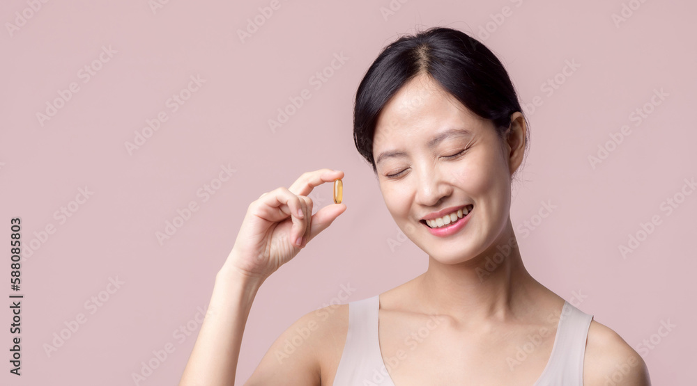 Portrait young asian woman happy smile face with vitamin nourishment pill. Pretty cute girl female person holding health capsule supplement skin care isolated on pink background. Medication concept. Portrait young asian woman happy smile face with vitamin nourishment pill. Pretty cute girl female person holding health capsule supplement skin care isolated on pink background. Medication concept.