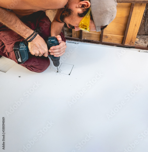 Wallpaper Mural Fit and focused: latino worker with work glasses (PPE) drilling holes in steel board (with big copy space) Torontodigital.ca