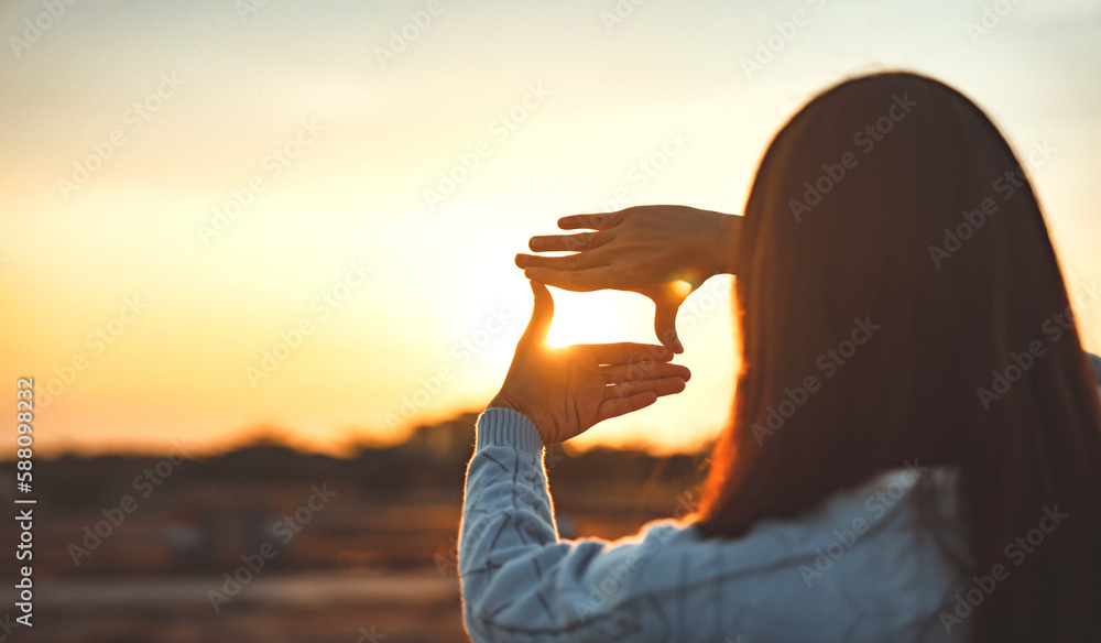 © oatawa - Woman hands making frame gesture with sunset, Female capturing the sunrise. Business planning, strategy and vision concept.