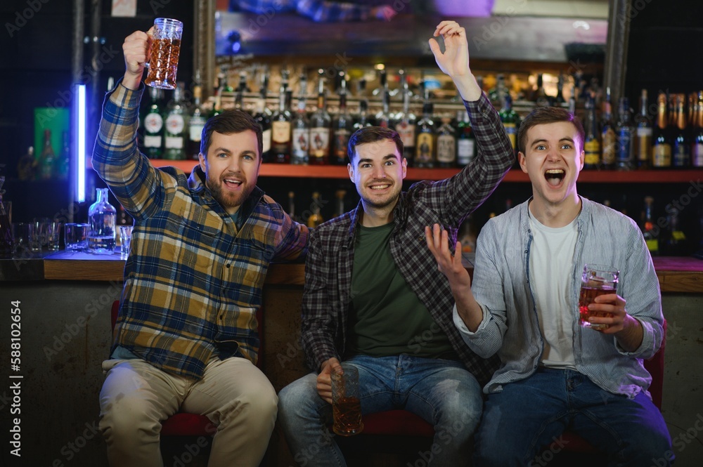Obraz premium Soccer fans at the bar. Happy football fans cheering at bar and drinking beer while bartender serving beer at the background