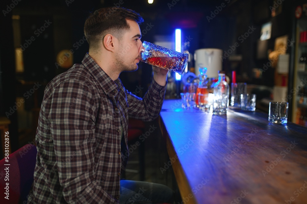Handsome bearded man drinking beer at the bar counter in pub