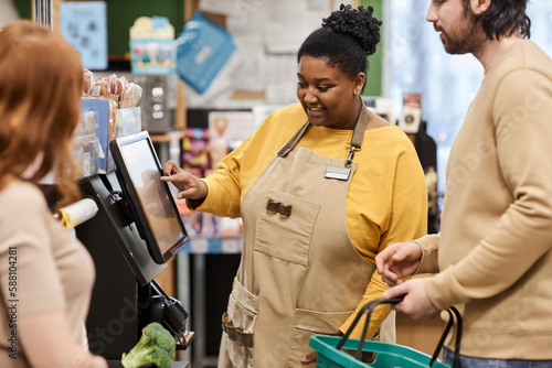 Schilderij op canvas Waist up portrait of smiling black woman helping customers with self checkout in
