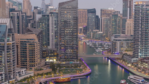 Dubai Marina with several boat and yachts parked in harbor and skyscrapers around canal aerial day to night timelapse.