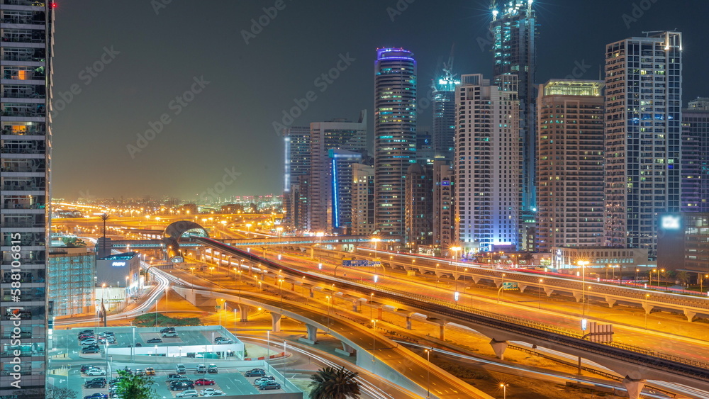 Dubai Marina skyscrapers and Sheikh Zayed road with metro railway aerial all night timelapse, United Arab Emirates