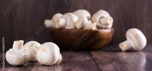 Close-up whole fresh champignons on a wooden table and in a bowl on the background web banner