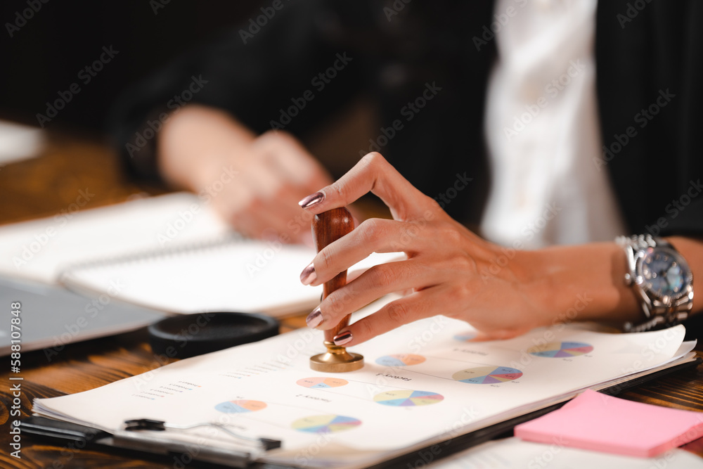 Person's hand stamping with approved stamp on certificate document