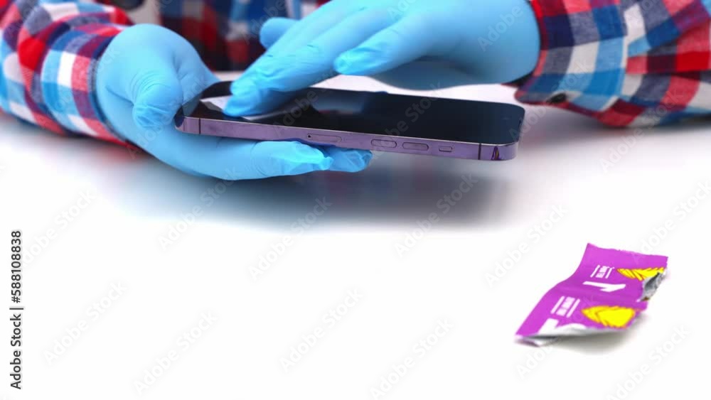 A male master glues a protective glass on a smartphone A male master glues a protective glass on a smartphone