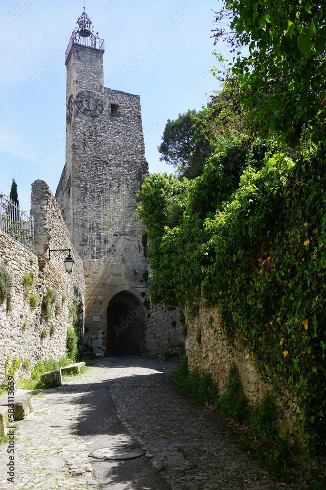 old stone chrch in the village with arch tunnel on the cobblestone street and green ivy wall in yhe town of Vaison la Romaine, south of France