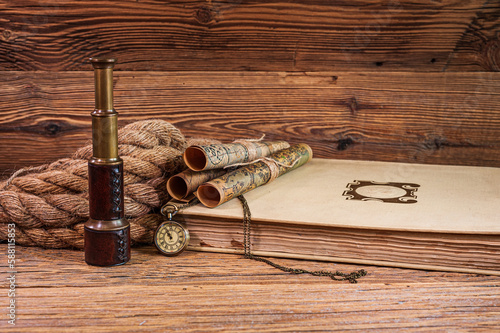 Old items, map scrolls and a pocket watch lying on an old book next to a thick rope and a telescope