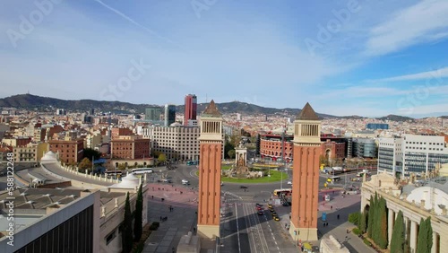 Panoramic aerial drone view of city traffic Plaza de Espana of Squares in Barcelona with Venetian Towers and Arenas de Barcelona. Cars driving around monumental fountain of Placa de Espanya. 4K video photo